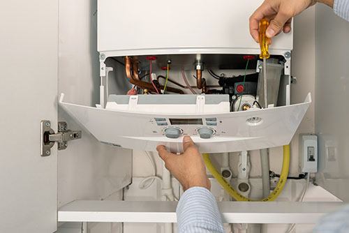 HVAC technician repairing an indoor boiler in El Mirage