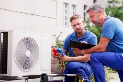 HVAC technicians reviewing an outdoor air conditioning unit in El Mirage, AZ